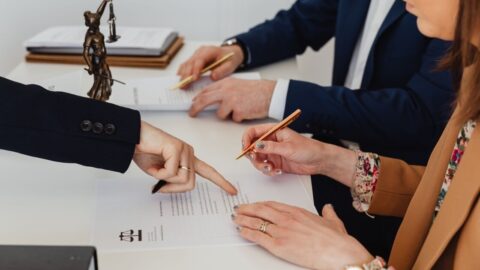 A woman signing a document with two people nearby