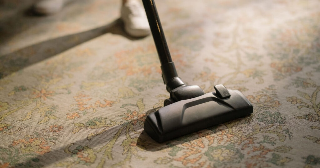 A vacuum cleaner head on a patterned floral carpet