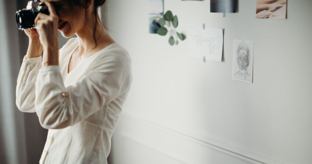 Woman taking a photo indoors with artistic decorations on the wall