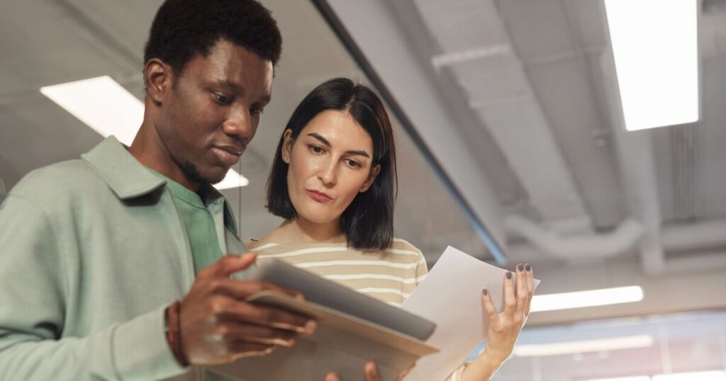 A man and woman reviewing a report on a tablet screen