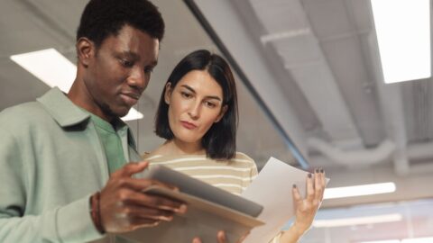 A man and woman reviewing a report on a tablet screen