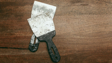 Two paint spatulas on a rustic wooden surface for artistic or construction use
