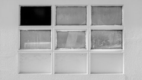 9 windows on a white wall with one broken