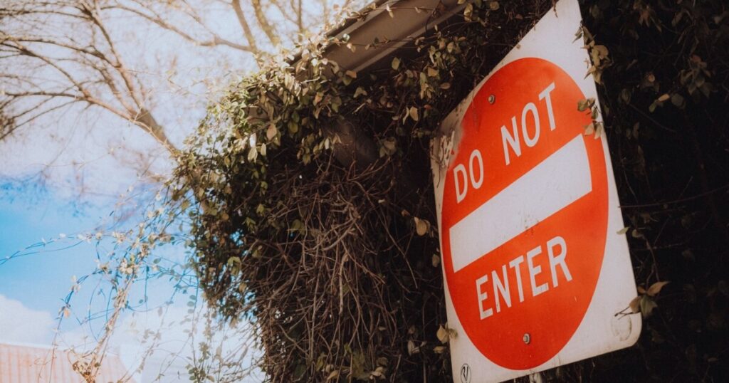 A red and white do not enter sign next to some foliage