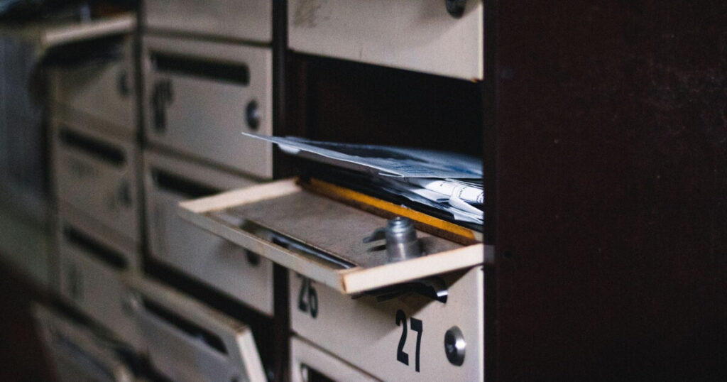 An open apartment mailbox with visible letters inside