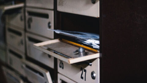 An open apartment mailbox with visible letters inside