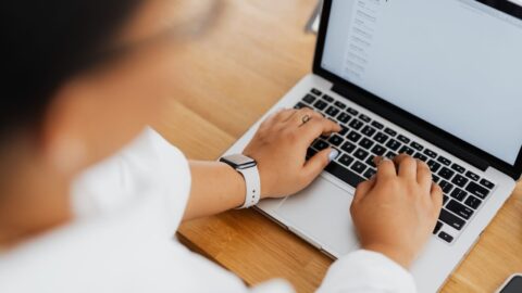 High angle shot of a person typing on a laptop, focused on hands and keyboard