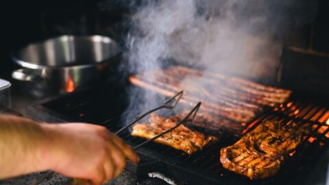 Close-up of grilling meat with smoke rising on a barbecue