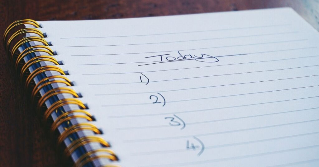 A close-up view of a handwritten to-do list on a spiral notebook with numbers for tasks