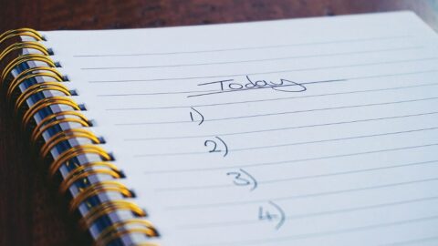 A close-up view of a handwritten to-do list on a spiral notebook with numbers for tasks