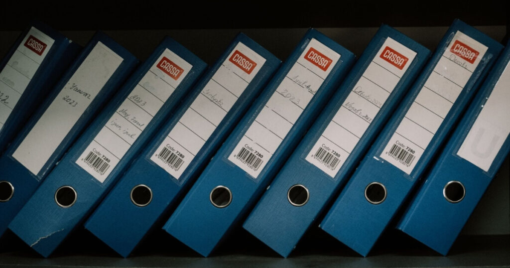 Neatly arranged blue office binders labeled with dates and names for organised storage
