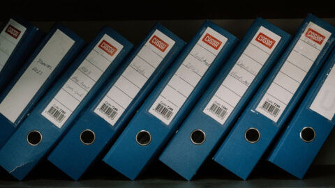 Neatly arranged blue office binders labeled with dates and names for organised storage