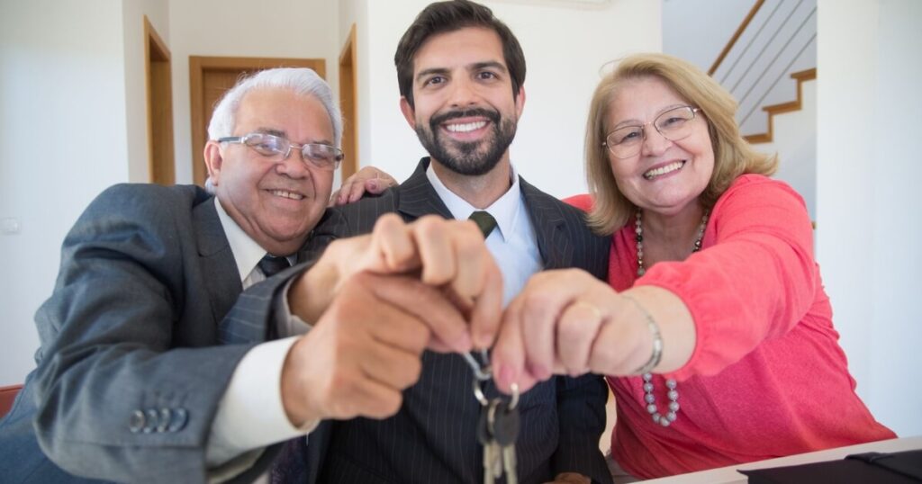 Smiling elderly couple receiving house keys from realtor indoors
