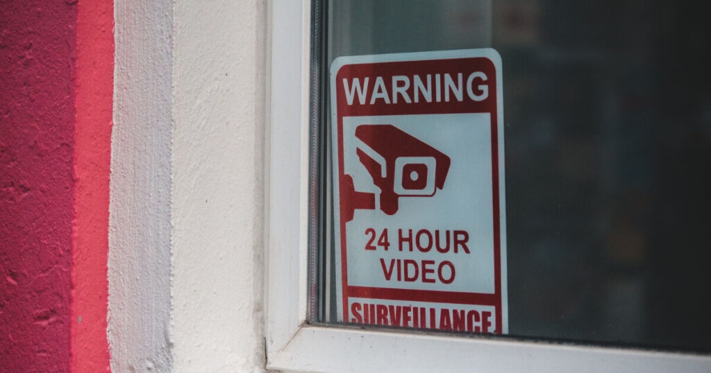 Close-up of a red warning sign for 24-hour video surveillance on a window