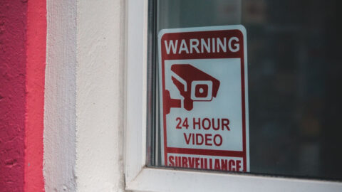 Close-up of a red warning sign for 24-hour video surveillance on a window