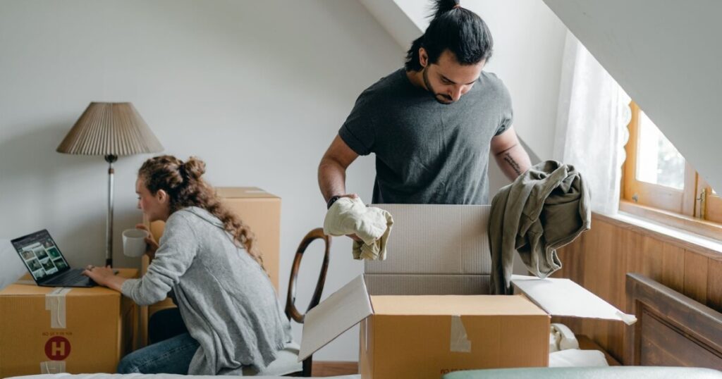 A couple moving into their new home, unpacking boxes and using a laptop for online browsing