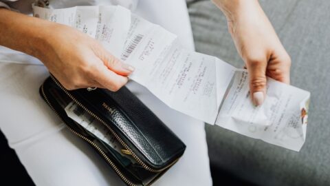 Close-up of a woman's hands managing multiple receipts taken from a black wallet