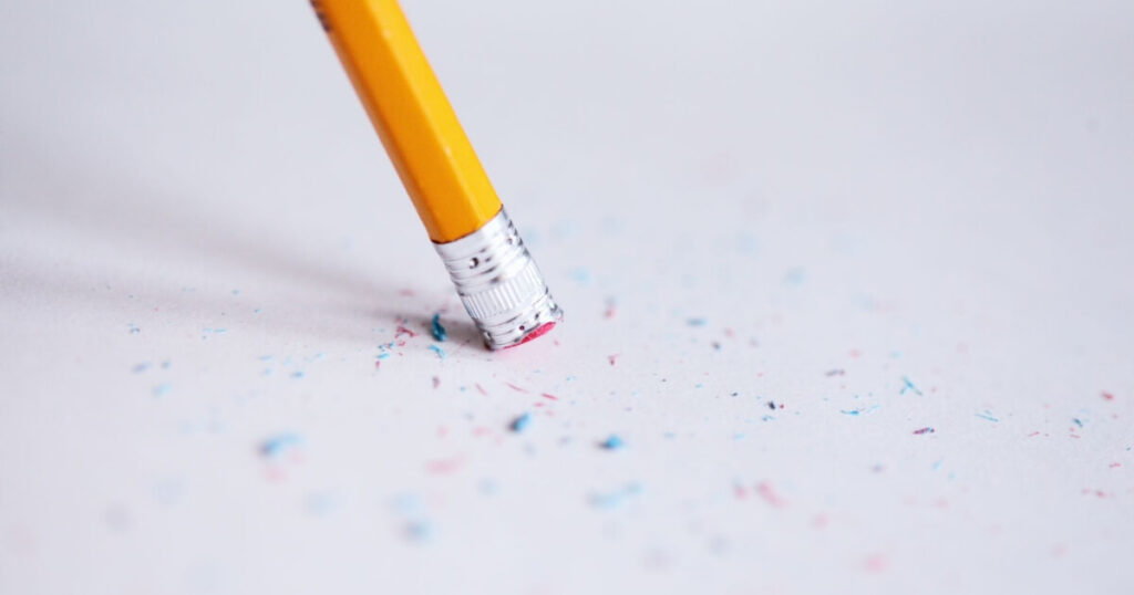 Macro shot of a yellow pencil erasing on paper with eraser shavings