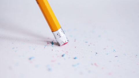 Macro shot of a yellow pencil erasing on paper with eraser shavings