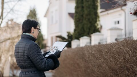 Landlord assessing house with clipboard during winter season outdoors