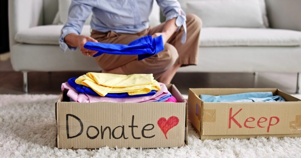A woman sorting clothes into a donate box and keep box