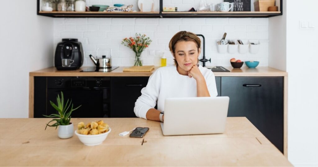 Adult woman focused on laptop work in a modern kitchen setting