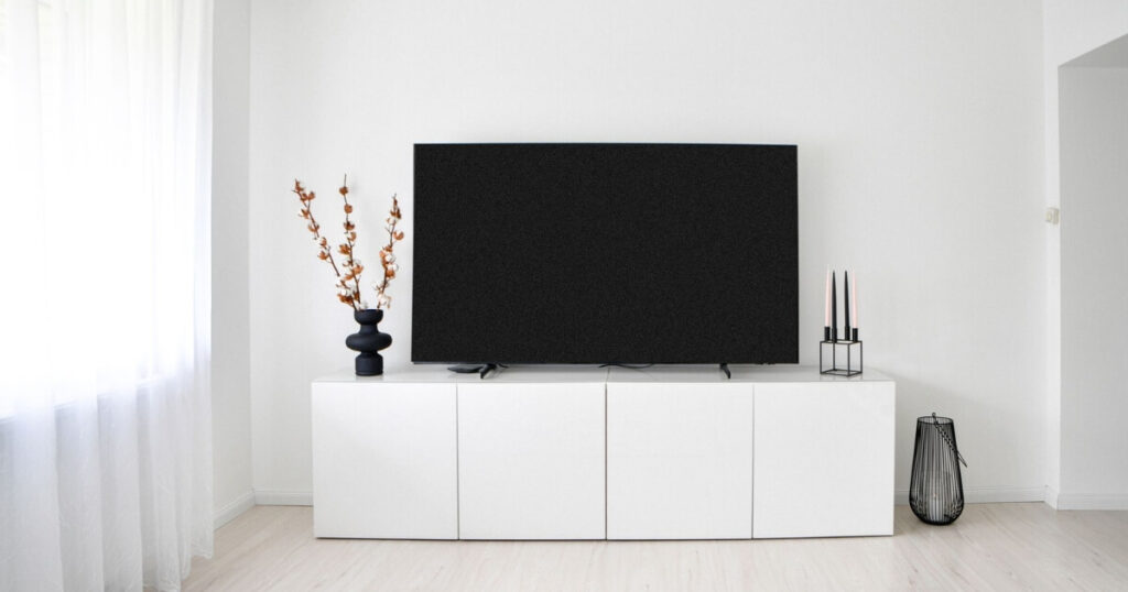 A sleek and minimalist Scandinavian living room with white decor and electronics