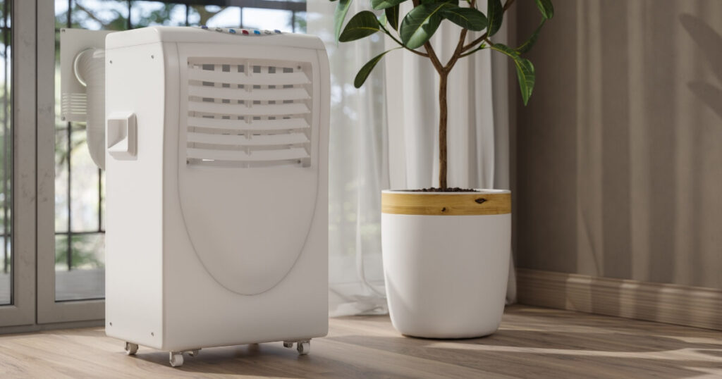 A white portable air conditioner next to a pot plant