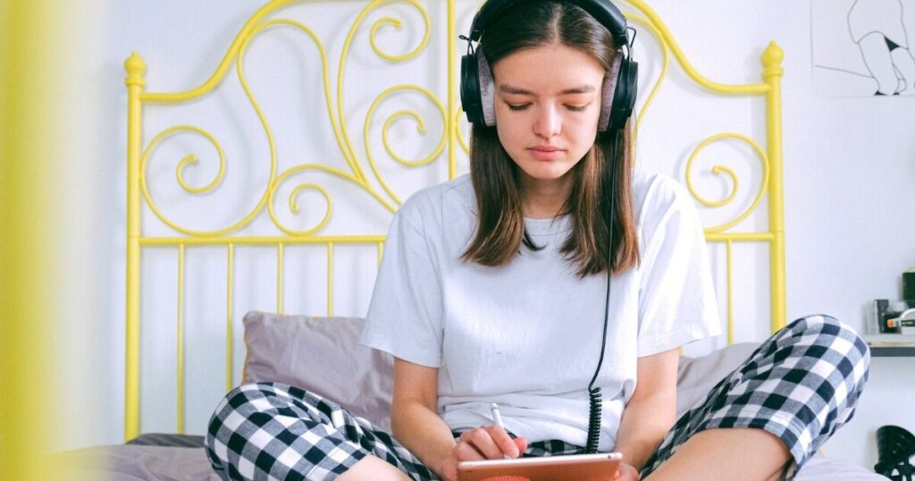 Young woman in pajamas working on a tablet in a bedroom
